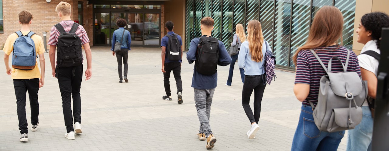 Junge Schülerinnen und Schüler strömen zum Schulhauseingang