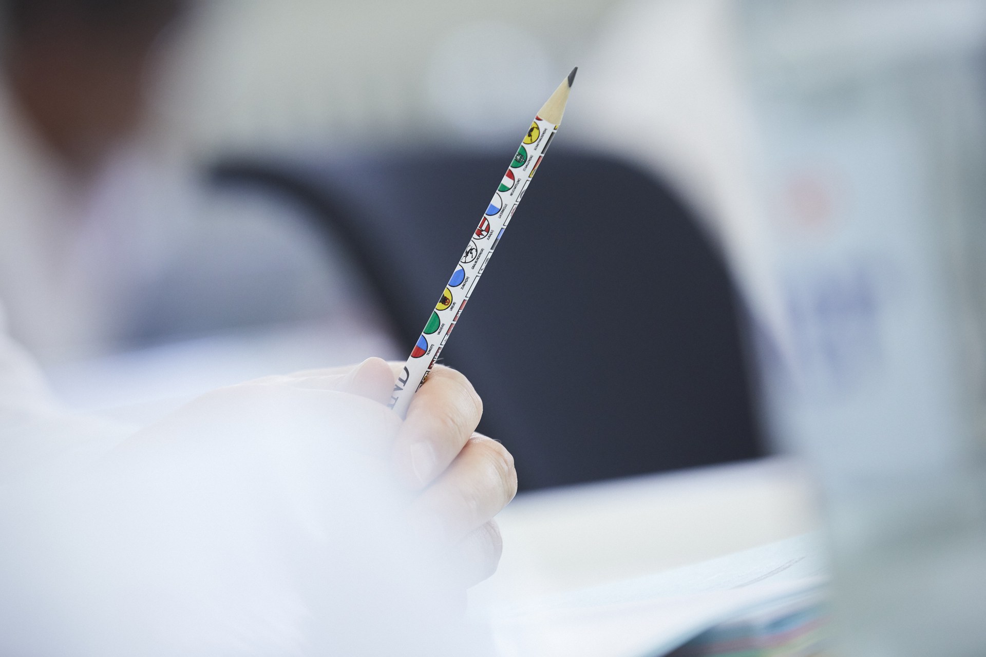 Hand hält Bleistift mit allen Kantonswappen drauf