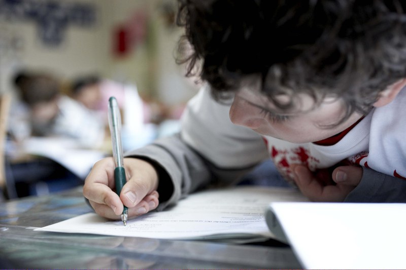 A child focuses on writing in an exercise book