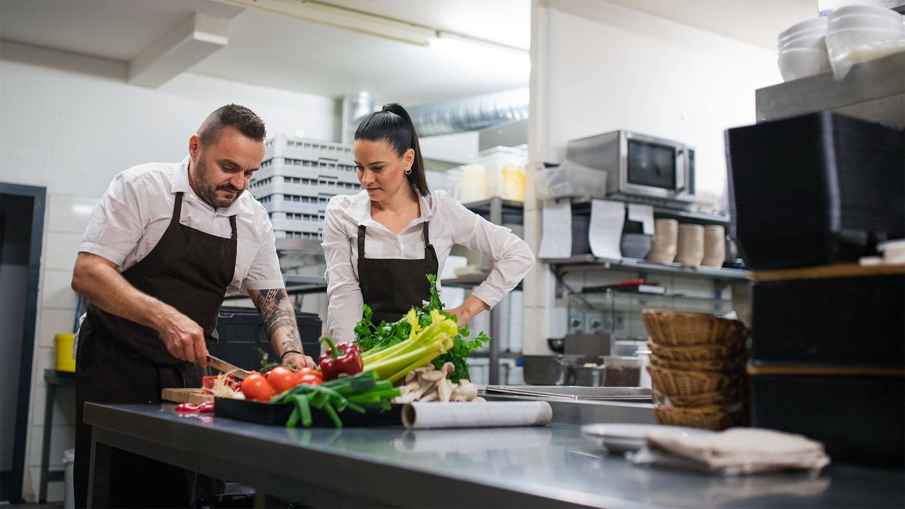 Un cuisinier explique quelque chose à une cuisinière dans une cuisine